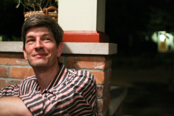 Graham Leuschke, seated on a porch in the evening